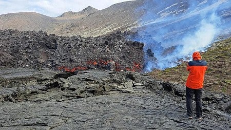 a man stands next to a lava flow